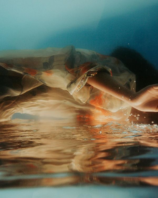 Woman performing a gentle, flowing movement in a bright, calm room.